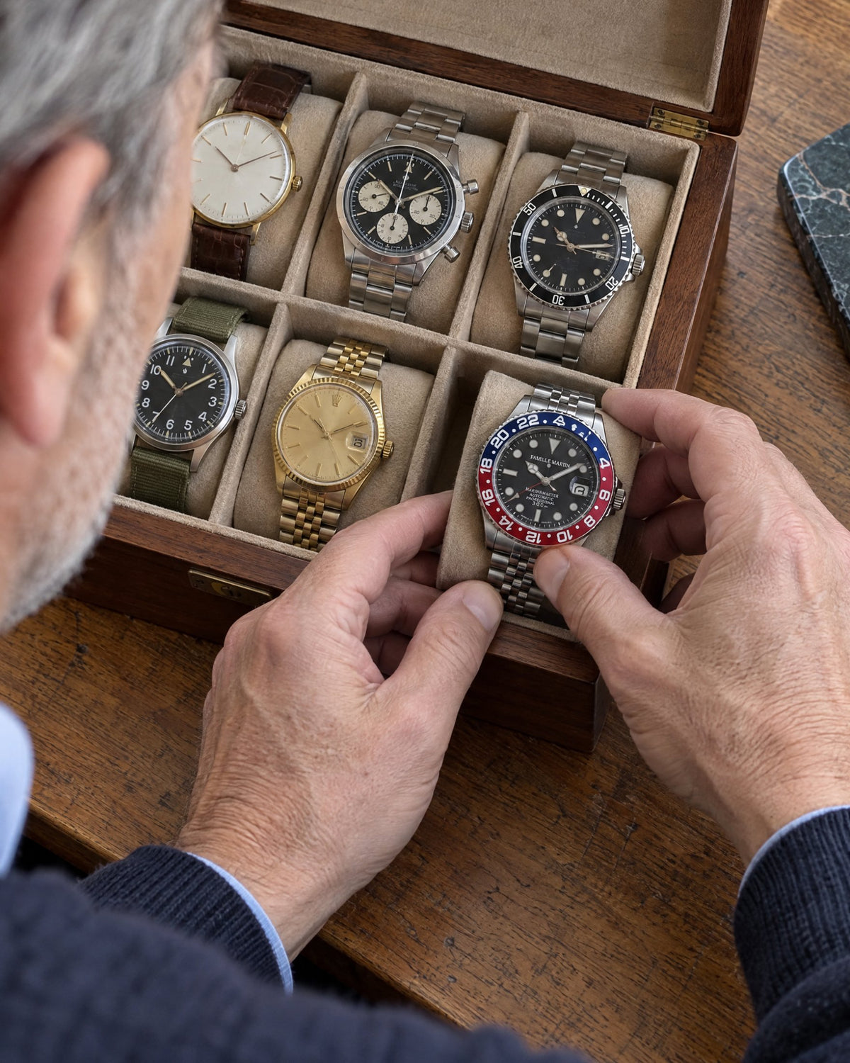 Un homme range une montre gravée dans sa boîte à montres
