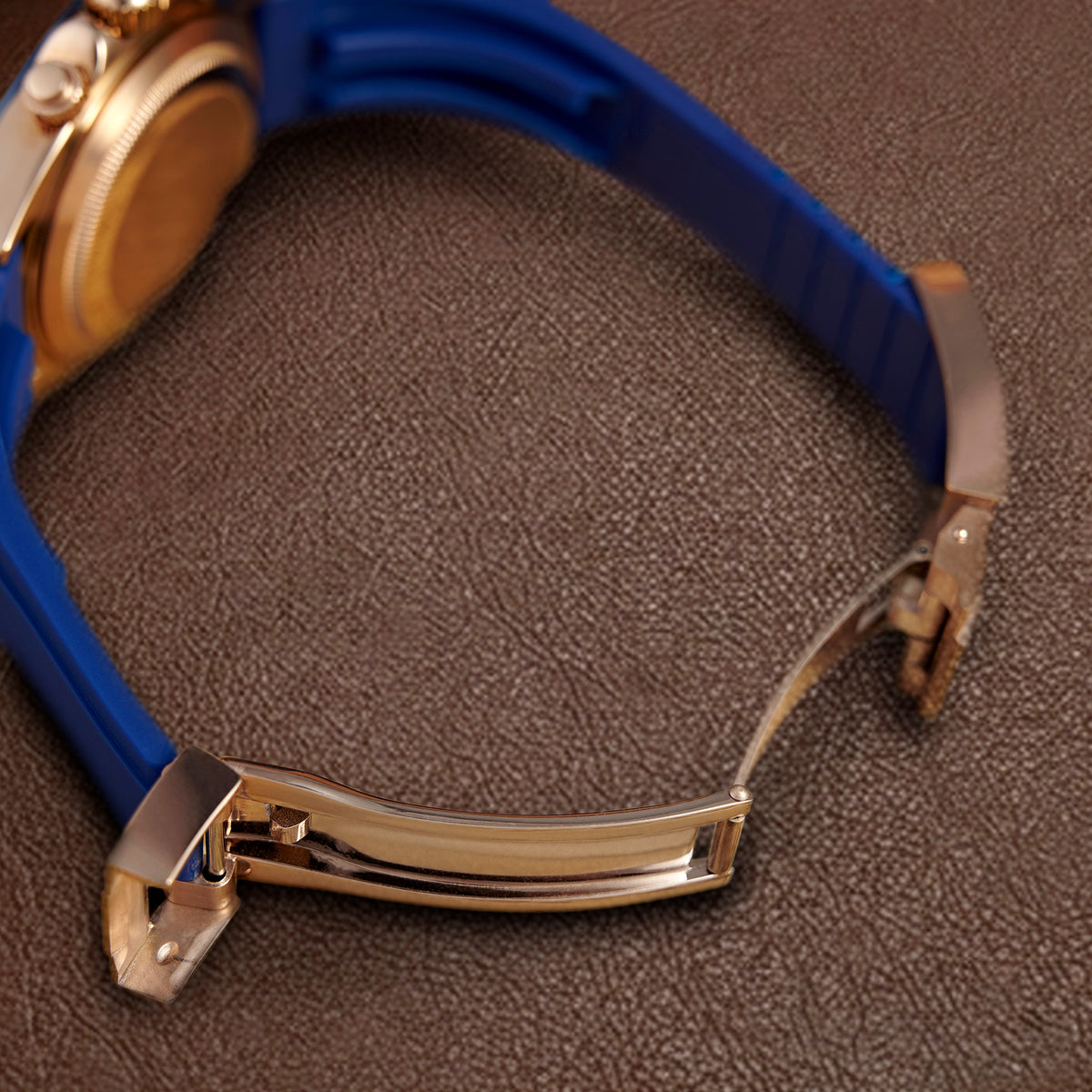 La boucle déployante couleur or rose sur le caoutchouc bleu